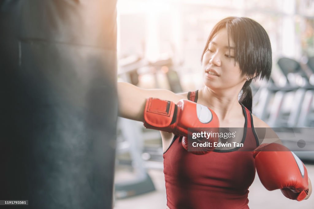 Una atleta adolescente asiática china que usa guantes de boxeo en el gimnasio durante el fin de semana