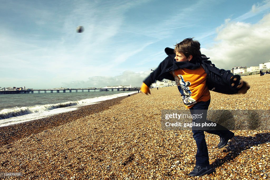 Boy throwing away stone on beach