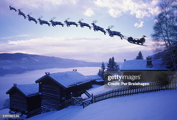 santa clause with reindeer flying above a farm - father christmas stock-fotos und bilder