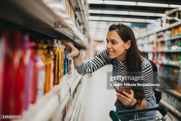 vrouw geniet van winkelen - boodschappenlijst stockfoto's en -beelden