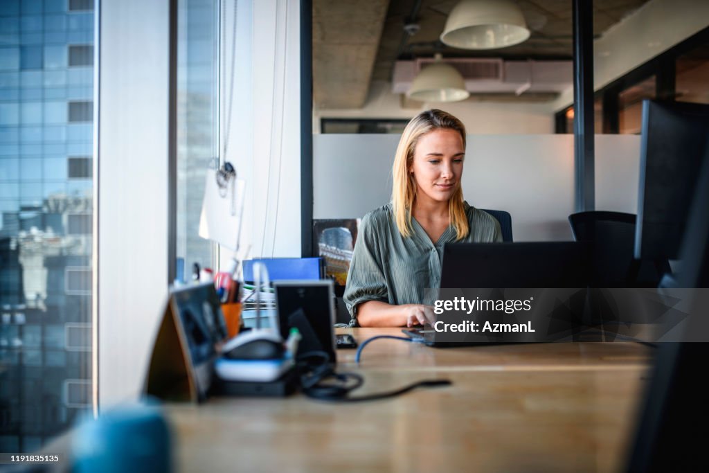 Focused Young Businesswoman Working on Laptop in Office