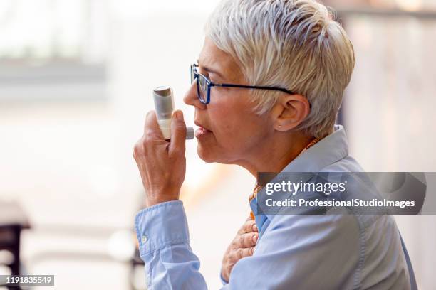 reife geschäftsfrau mit asthma-inhalator - bronchialbaum stock-fotos und bilder