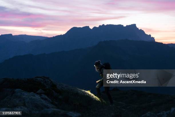 female hiker crosses mountain ridge at sunrise - flashlight stock pictures, royalty-free photos & images