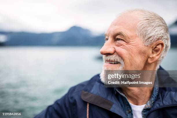 cheerful senior man tourist standing by lake in nature on holiday. - senior men laughing stock pictures, royalty-free photos & images