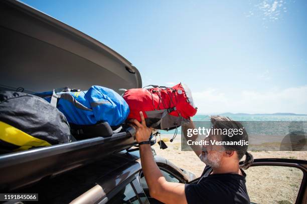 männer packen cargo box container auf dachträger im urlaub - luggage rack stock-fotos und bilder