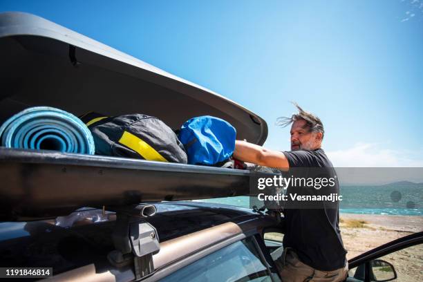 men packing cargo box container on roof rack on vacations - car roof stock pictures, royalty-free photos & images
