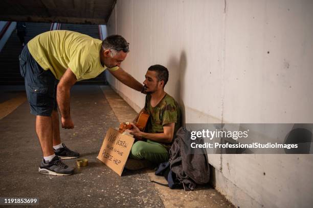 kind man is giving donation to street guitarist - homeless person imagens e fotografias de stock