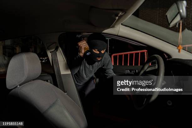 en tjuv klädd i svart med balaclava på huvudet försöker stjäla bilen från stadens gator - kapa bildbanksfoton och bilder