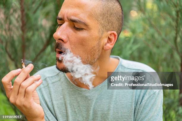 cannabis verslaafde is genieten in marihuana sigaret in het openbare park - stick plant part stockfoto's en -beelden