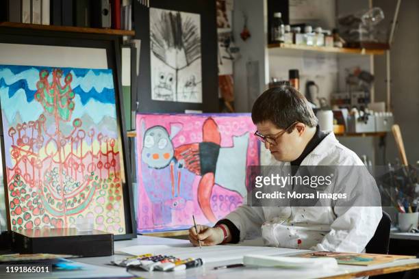 male artist with down syndrome drawing in studio - international artists stock pictures, royalty-free photos & images