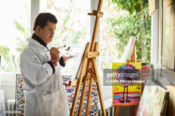 man with down syndrome painting on canvas - international artists stock pictures, royalty-free photos & images