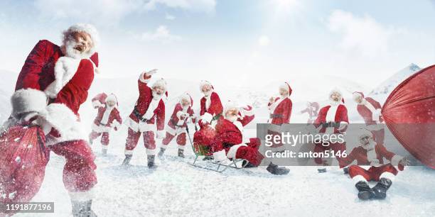 santa clauses pulling bags of presents on sled in snowly winter on background - christmas gift bag stock pictures, royalty-free photos & images