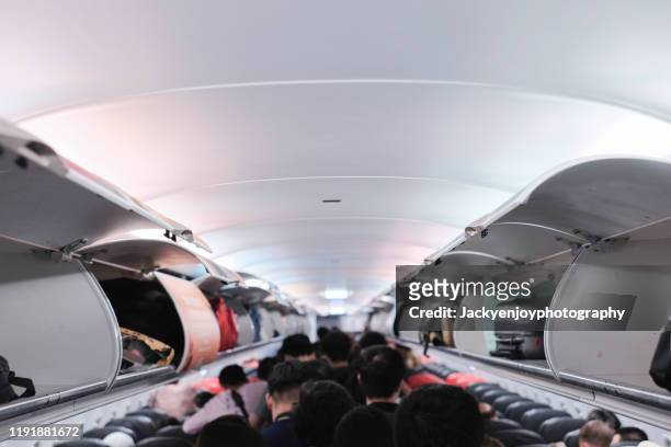 overhead locker on airplane,passenger put cabin bag cabin on the top shelf. travel concept - boarding plane stockfoto's en -beelden
