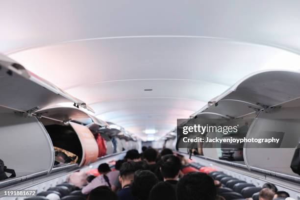 overhead locker on airplane,passenger put cabin bag cabin on the top shelf. travel concept - embarks stock pictures, royalty-free photos & images