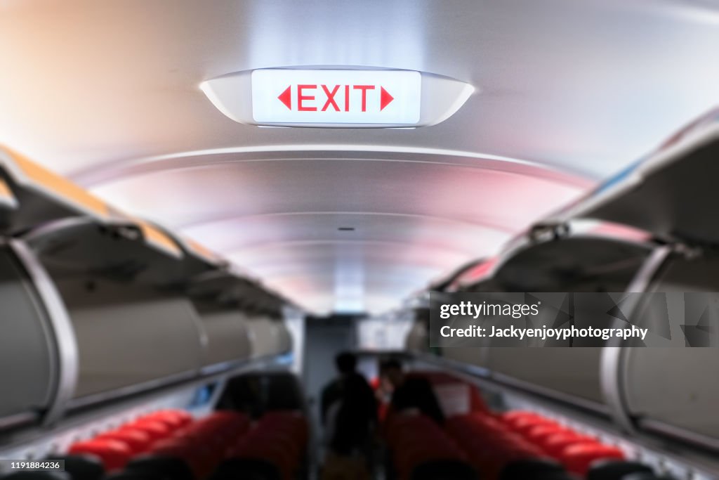 Emergency exit sign on ceiling inside passenger aircraft cabin
