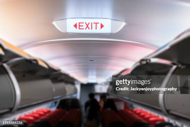 emergency exit sign on ceiling inside passenger aircraft cabin - inside of airplane stock pictures, royalty-free photos & images