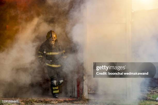 firefighter in fire fighting operation. - militante gruppe stock-fotos und bilder