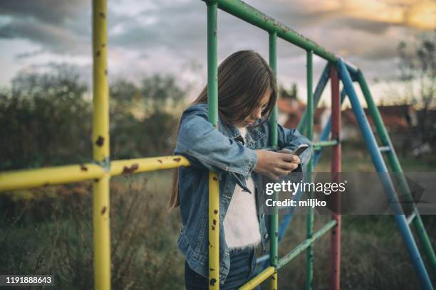 teenage girl on playground with mobile phone - abandon stock pictures, royalty-free photos & images