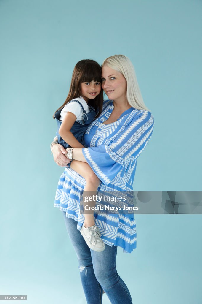 Mother carrying her child against pale blue background