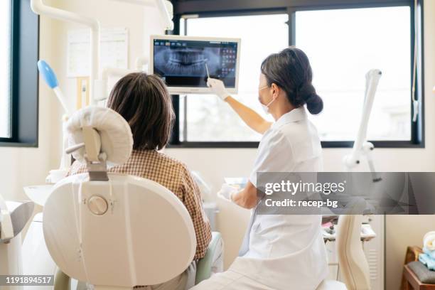 患者にx線について説明する女性歯科医師 - 歯科医院 ストックフォトと画像