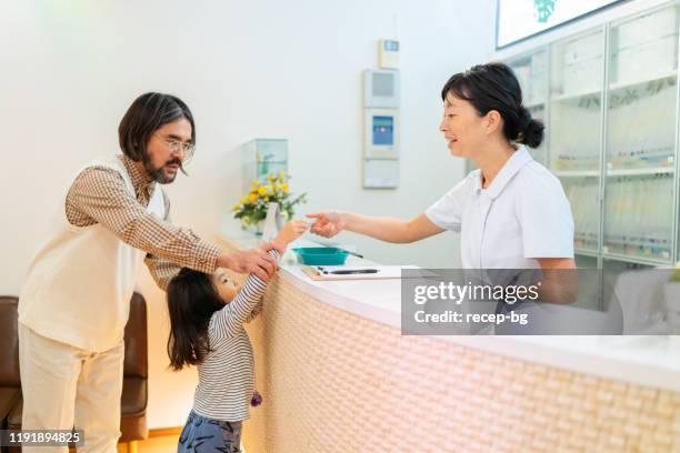 father and daughter at hospital reception - asian receptionist stock pictures, royalty-free photos & images