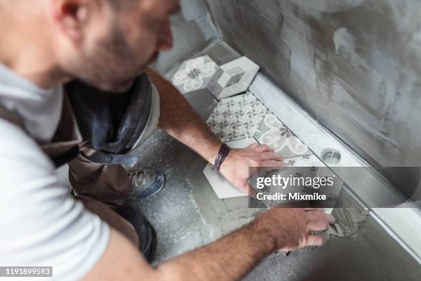 tiler instalando baldosas en el suelo del baño - baldosa fotografías e imágenes de stock