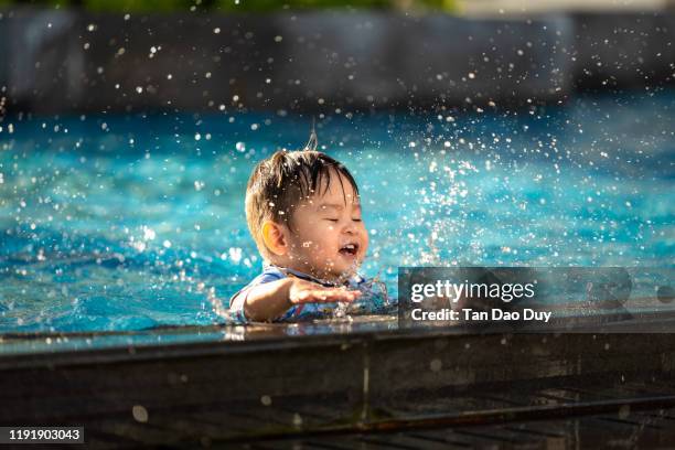 vietnamese - happy child playing with water splashes in the pool - baby blue eyes stock pictures, royalty-free photos & images