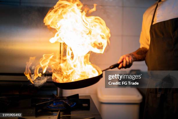 chef bereidt vlam meel met behulp van pan in een commerciële keuken - chef kitchen stockfoto's en -beelden