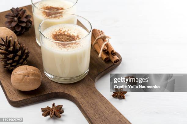 eggnog in glasses with star anise, cinnamon and walnuts and fir cones on a white wooden background. - anise plant stockfoto's en -beelden