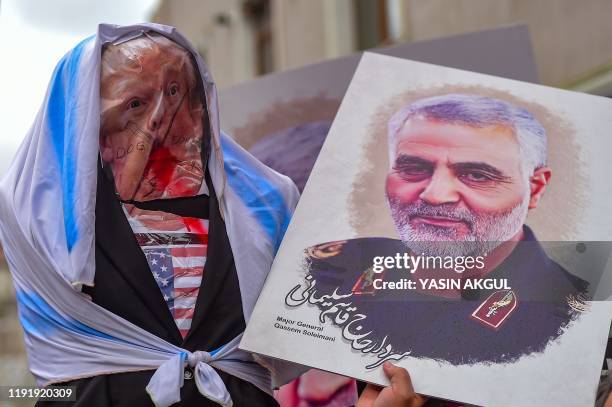 Protesters hold an effigy of US President Donald Trump and a picture of Iranian commander Qasem Soleimani, during a demonstration outside the US...