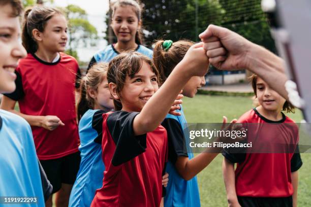 team von weiblichen und männlichen kindern zusammen auf einem fußballplatz - child saluting stock-fotos und bilder