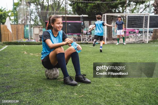 jeune fille s'asseyant sur un bille de football, se reposant de la formation - coach bus photos et images de collection