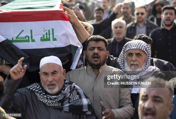 Iraqis carry a mock coffin as they march in a symbolic funeral procession for senior Iraqi military figure Abu Mahdi al-Muhandis, in the southern...