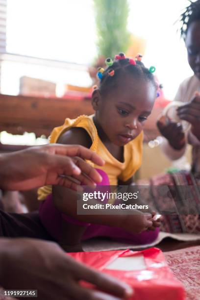 kleines mädchen konzentriert sich auf klebeband auf weihnachtsgeschenke - zimbabue stock-fotos und bilder