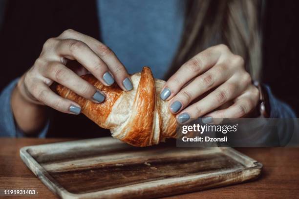 mujer desgarrando croissant dulce - pan dulce fotografías e imágenes de stock