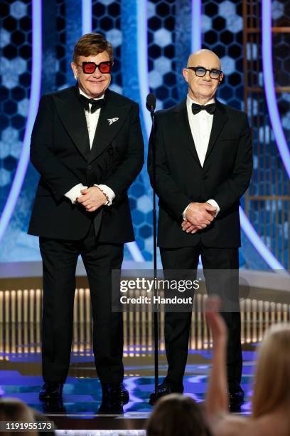 In this handout photo provided by NBCUniversal Media, LLC, Sir Elton John and Bernie Taupin speak onstage during the 77th Annual Golden Globe Awards...