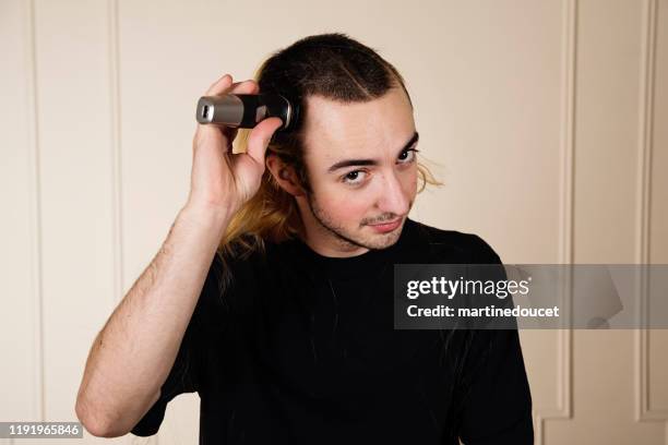 portrait of millennial young man shaving his hair. - shaving head stock pictures, royalty-free photos & images