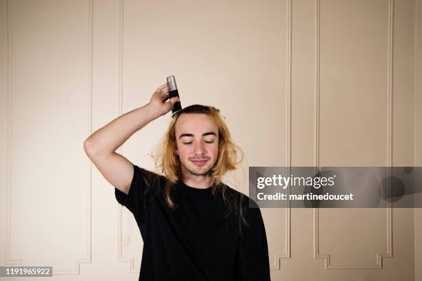 portrait of millennial young man shaving his hair. - head shave stock pictures, royalty-free photos & images