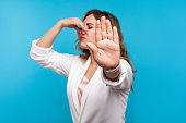 Bad smell. Portrait of woman pinching her nose and showing stop gesture, expressing disgust to unpleasant odor. blue background