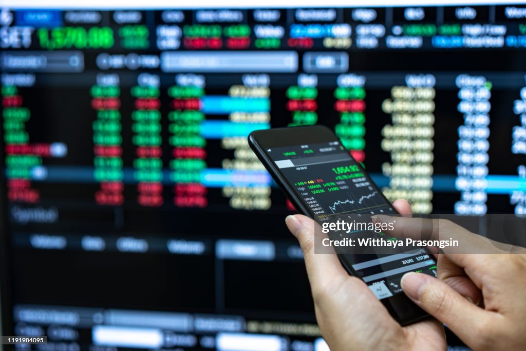 Businessman checking stock market data. He using a mobile phone. Analysis economy data on forex earn graph.