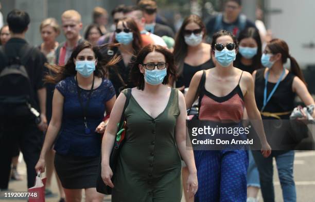 People are seen wearing face masks to protect from smoke haze as they cross a busy city street on December 05, 2019 in Sydney, Australia. Smoke haze...