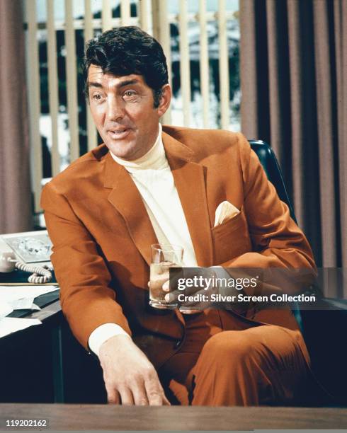 Dean Martin , US singer and actor, wearing a brown suit and holding a drink in a publicity portrait issued for the film, 'The Silencers', USA, 1967....