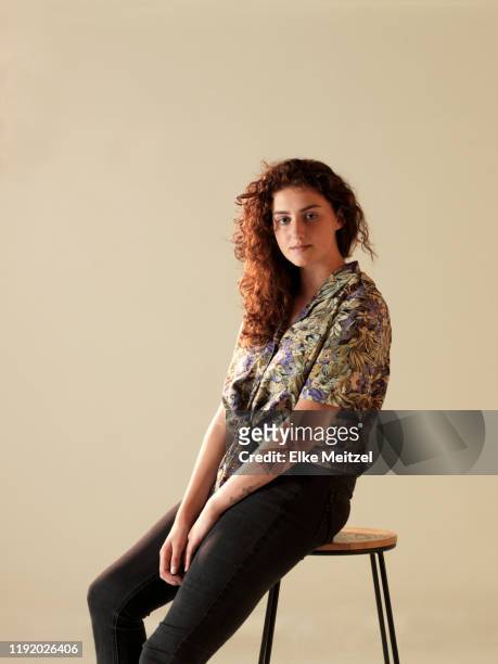 portrait of young woman sitting on a chair - chairs in studio stockfoto's en -beelden