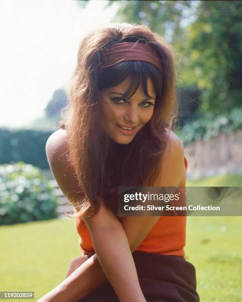 Claudia Cardinale, Italian actress, wearing an orange top and brown headband, with her arms crossed in front of her, circa 1960.