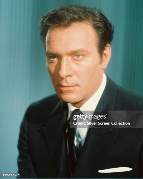 Christopher Plummer, Canadian actor, wearing a black jacket, white shirt and black tie in a studio portrait, against a blue background, circa 1960.