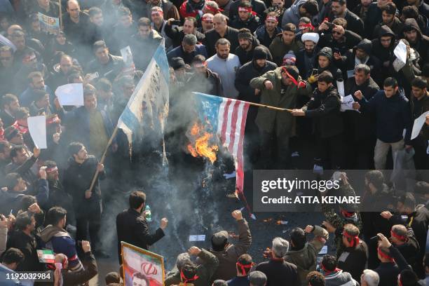Iranians set a US and an Israeli flag on fire during a funeral procession organised to mourn the slain military commander Qasem Soleimani, Iraqi...