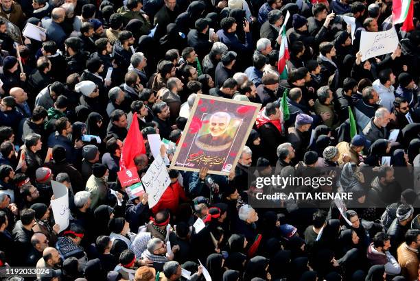 Iranian mourners lift a picture of slain military commander Qasem Soleimani during a funeral procession in the capital Tehran on January 6 for him as...