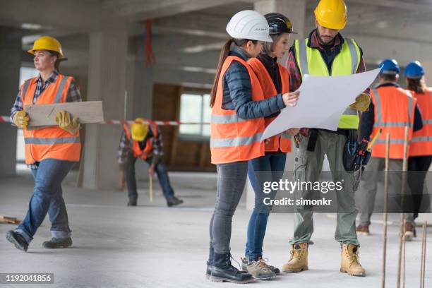 architekten diskutieren blaupause mit bauarbeiter - arbeitsstiefel stock-fotos und bilder