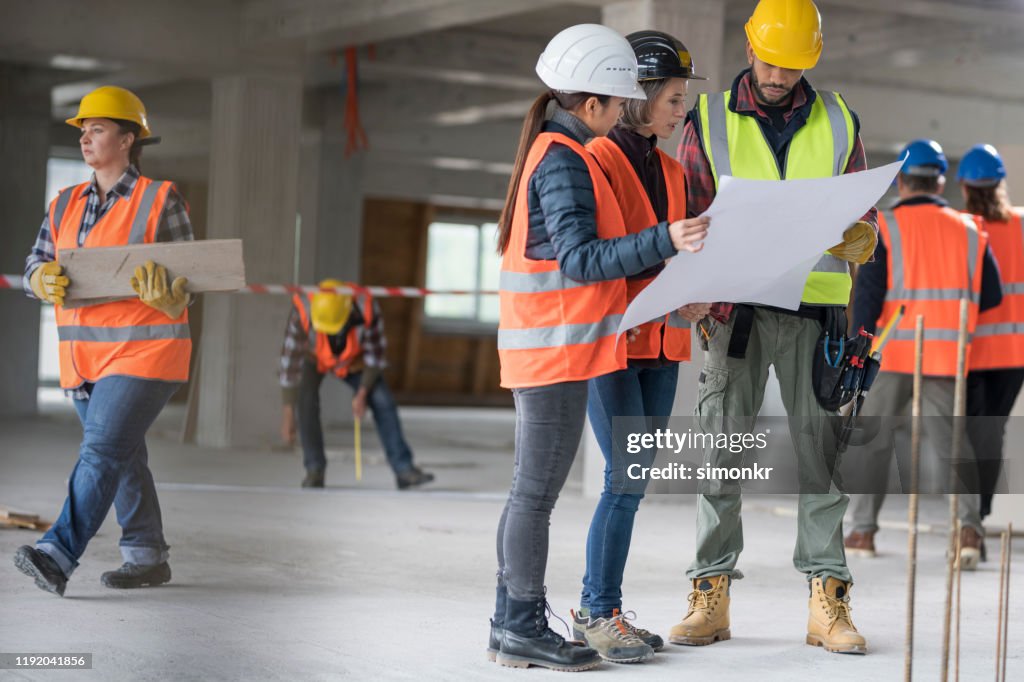 Architects discussing blueprint with construction worker