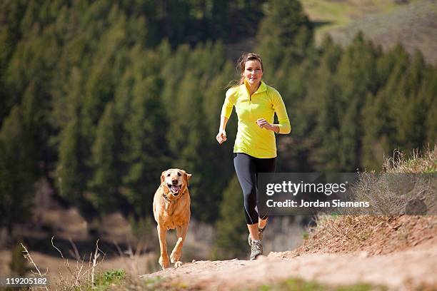 female trial running with her dog. - yellow labrador retriever photos et images de collection